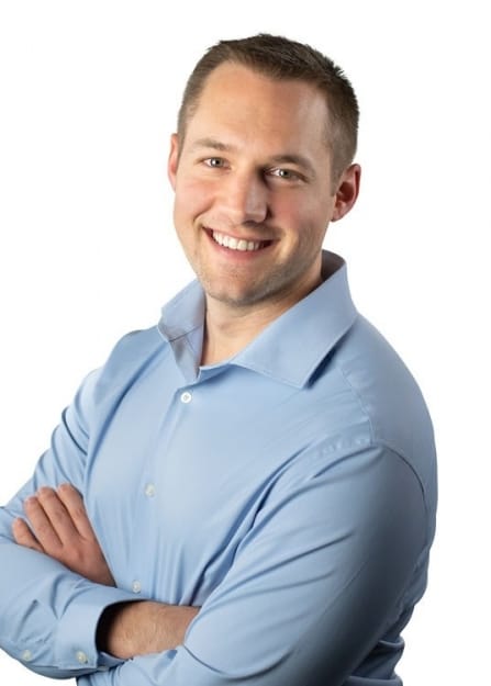Josh Shaw RMT photo of a smiling man in a blue collared shirt with his arms crossed